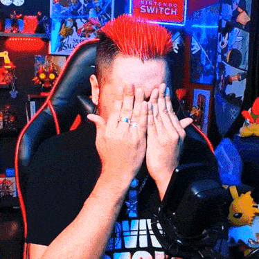 a man covering his face with his hands in front of a nintendo switch sign