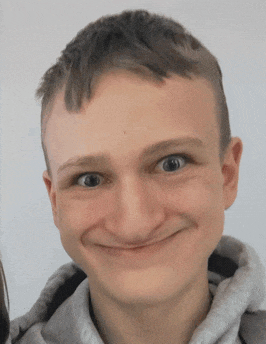 a young man wearing a grey hoodie is smiling