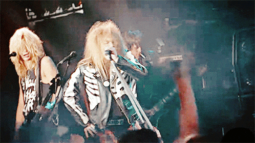 a man in a skeleton jacket sings into a microphone in front of a crowd