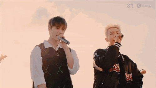 a person is singing into a microphone while another person plays a flute in the background .