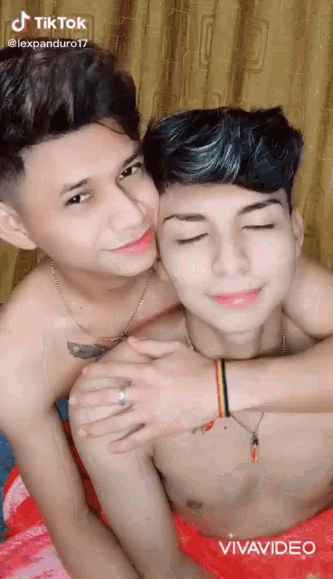 two shirtless boys are hugging each other with their eyes closed