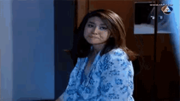 a woman in a blue floral robe is standing in front of a door .
