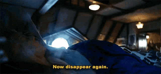 a person laying on a bed with the words `` now disappear again '' written on the bottom of the screen .