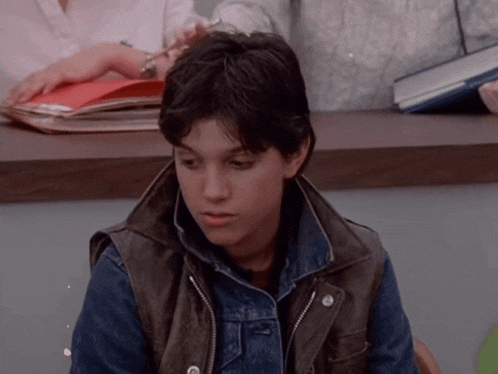 a young boy wearing a leather vest and denim jacket