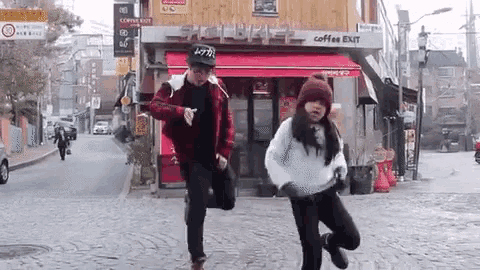 a man and a woman are dancing on a street in front of a coffee shop .