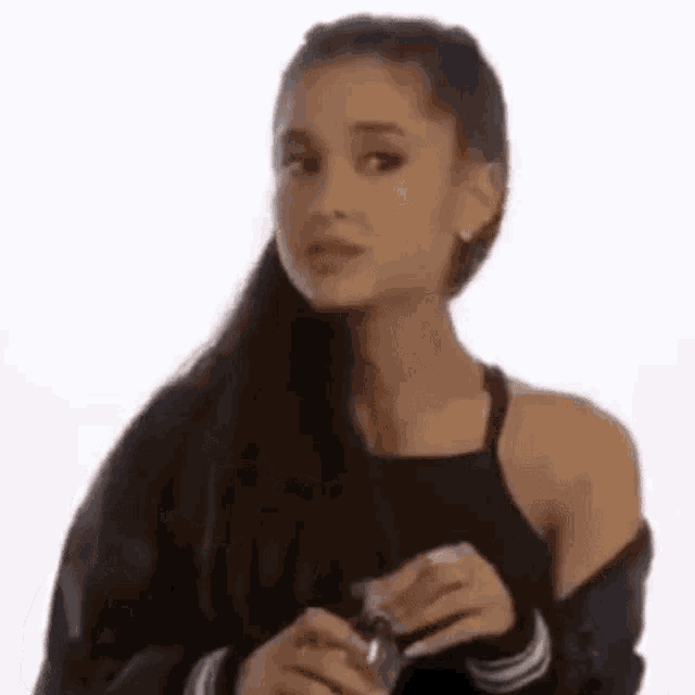 ariana grande is wearing a black tank top and a black jacket while holding a bottle .