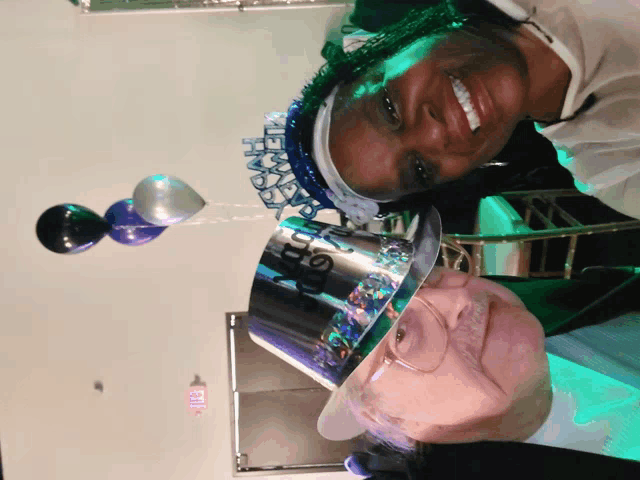 a woman wearing a new year 's eve hat smiles next to an older man