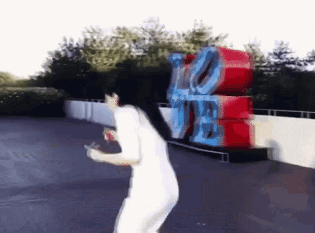 a woman in a white outfit is standing in front of a large love sign
