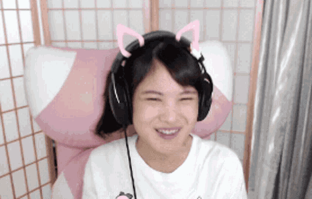 a girl wearing headphones with cat ears on her head is smiling