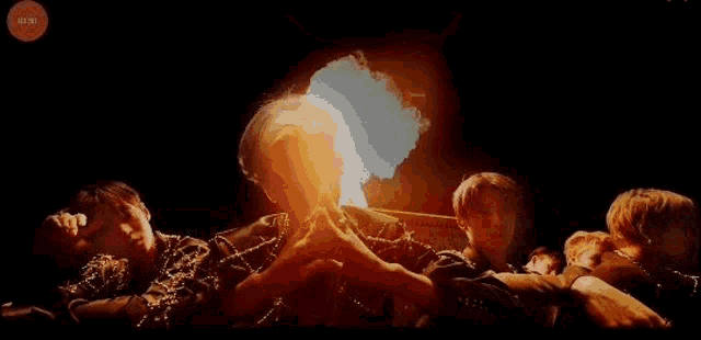 a group of people are holding hands in a dark room with a glowing light behind them .