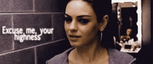 a woman stands in front of a brick wall with the words excuse me your highness above her