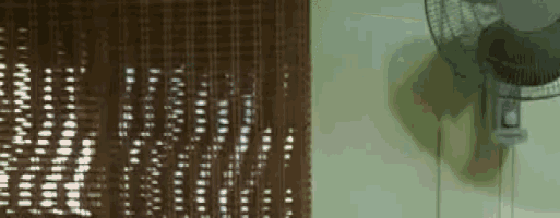 a fan is hanging on a wall next to a brown crocheted curtain