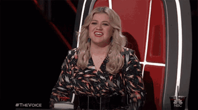 a woman is sitting in a chair with a cup of soda in front of her that says nbc