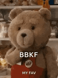 a teddy bear wearing a red apron is standing in a fridge .