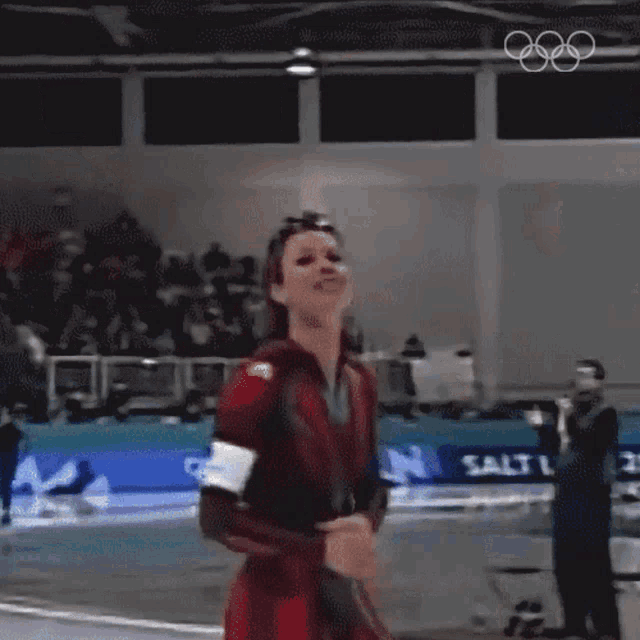 a woman stands with her arms in the air in front of a sign that says ' olympics '