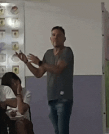 a man is standing in front of a group of people in a classroom and giving a presentation .