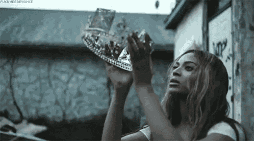 a woman is holding a crown in her hands while standing in front of a building .