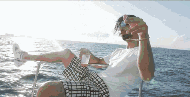 a man sits on a boat with his feet up drinking a drink