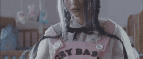 a woman is wearing a pink overall with the word baby on it