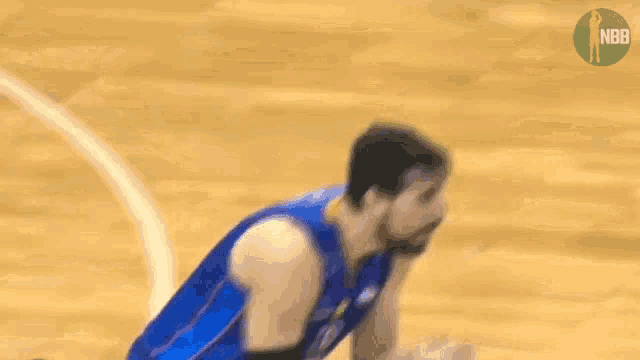 a basketball player in a blue uniform is kneeling down on the court