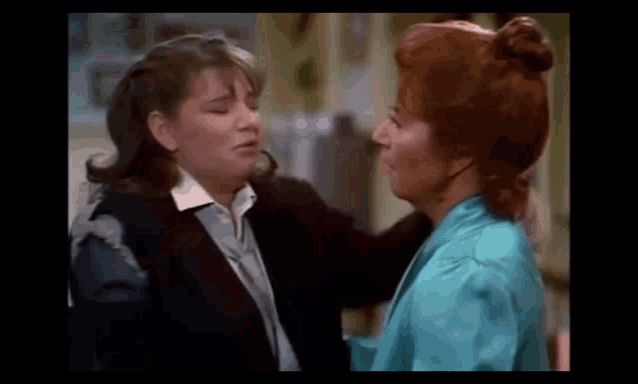 two women are standing next to each other and hugging .