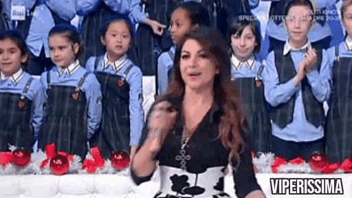 a woman is standing in front of a group of children wearing blue uniforms .
