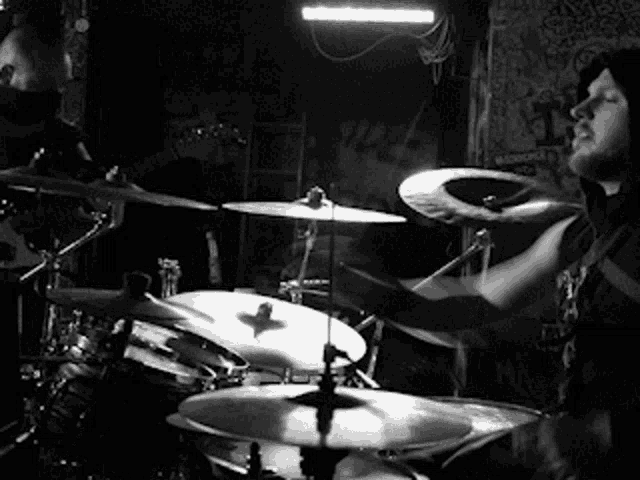 a man is playing drums in a dark room