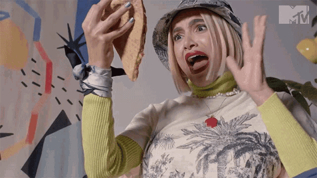 a woman is holding a sandwich in front of a tv screen