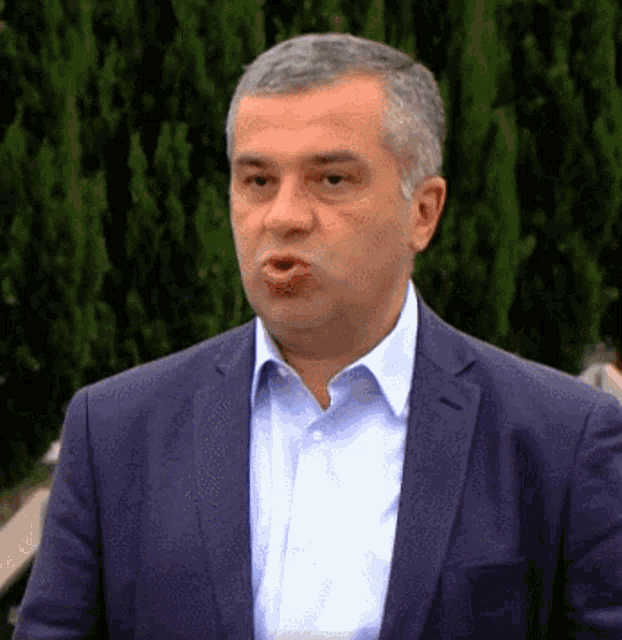 a man in a suit and white shirt is making a face