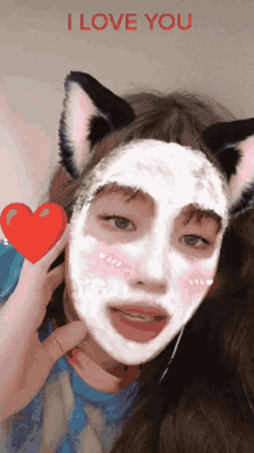 a girl with a cat ear and a white mask on her face holds a red heart and says i love you