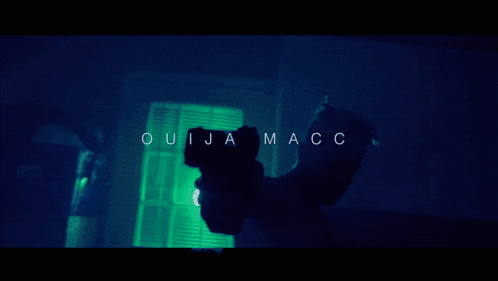 a person standing in front of a window with the words ouija macc written on the bottom