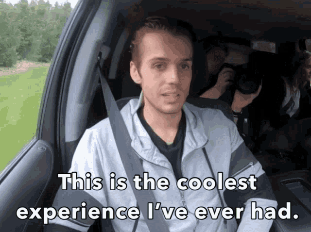 a man in a car with the words " this is the coolest experience i 've ever had " above him