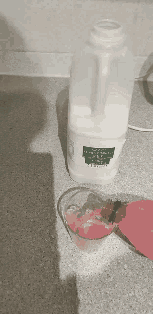 a bottle of semi-skimmed milk sits next to a measuring cup of pink liquid
