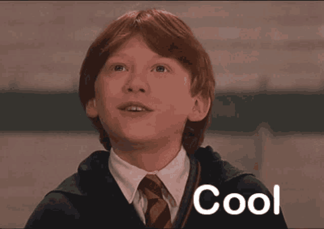 a young boy with red hair is wearing a suit and tie and the word cool is on the bottom
