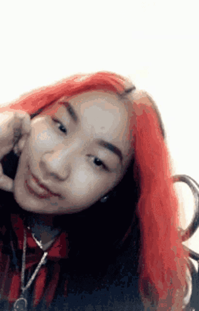 a young woman with red hair is making a funny face while wearing a necklace .