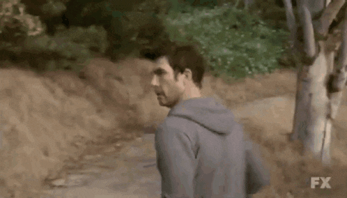 a man in a suit is walking down a dirt road .