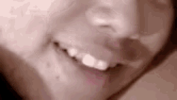 a close up of a person 's face smiling with a blurred background .