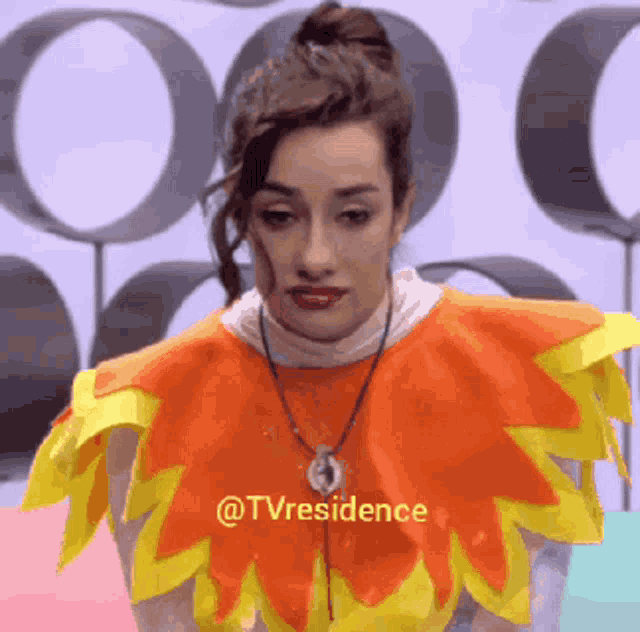 a woman wearing an orange and yellow costume with the words @tvresidence on it