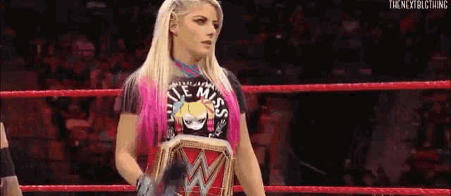 a woman is standing in a wrestling ring holding a championship .