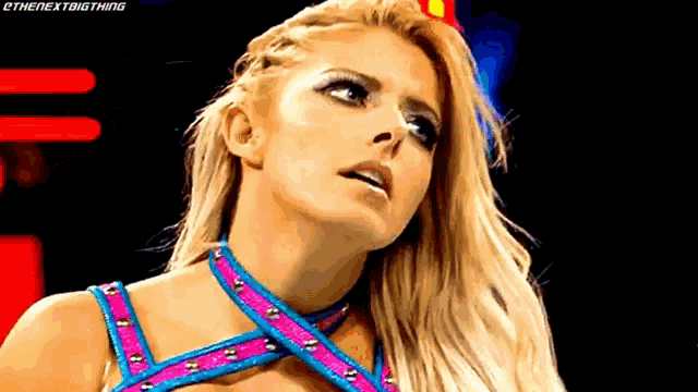 a female wrestler is wearing a pink and blue outfit and looking up at the sky .