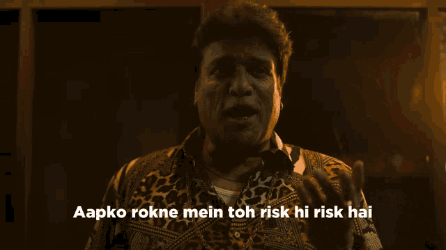a man in a leopard print shirt says aapko rokne mein toh risk hi risk hai in a dark room
