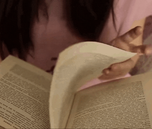 a woman is reading a book with a foreign language on the page