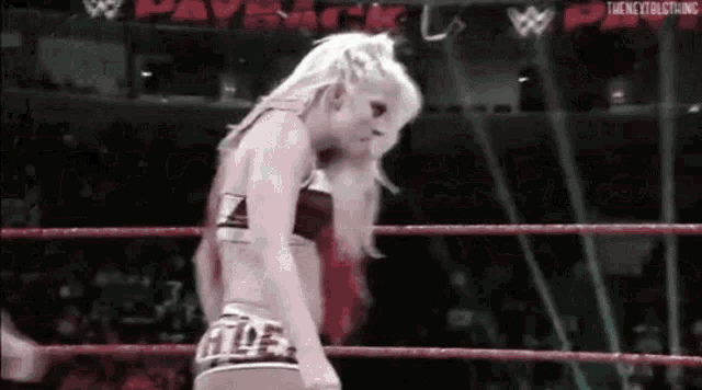 a woman is standing in a wrestling ring with her head down .