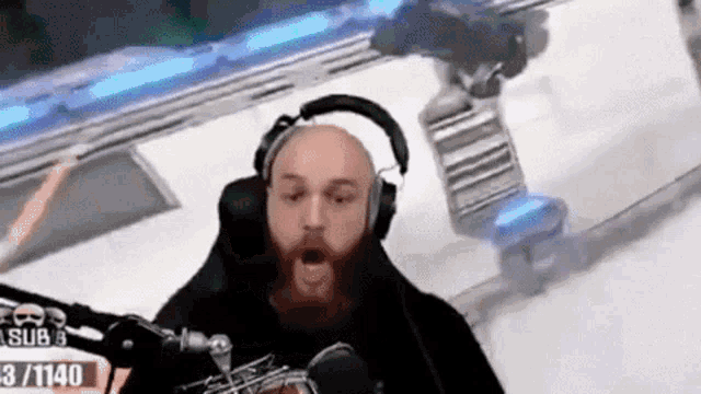 a bald man with a beard is wearing headphones and a microphone .