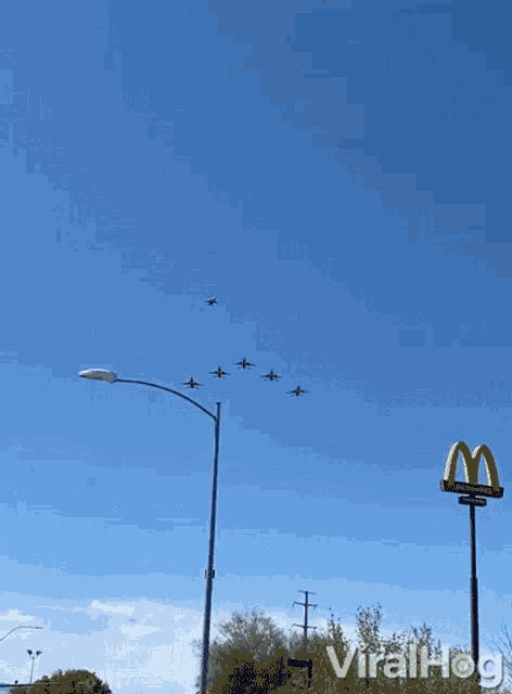 a mcdonald 's sign is in the foreground of a group of planes in the sky