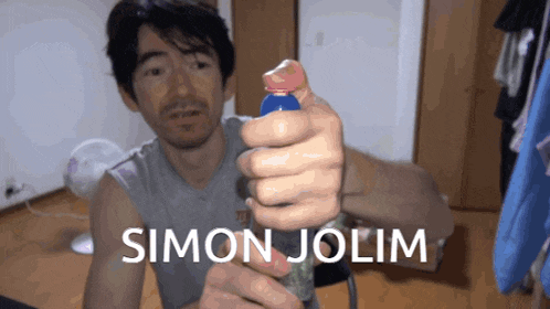 a man is holding a bottle with the name simon jolim on the bottom