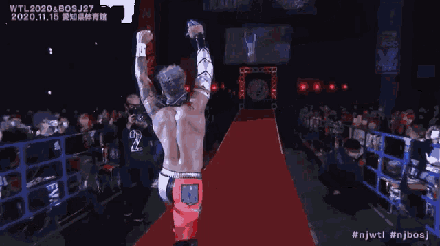 a wrestler with the number 2 on his back is walking down a red carpet