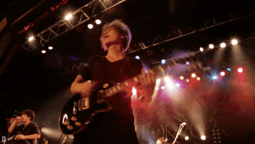 a man playing a guitar on a stage with a sign that says d on it