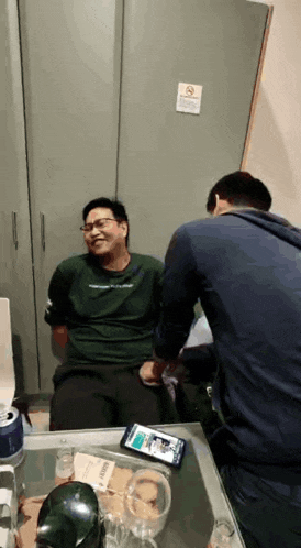 a man in a green shirt is laughing in front of a no smoking sign on the wall