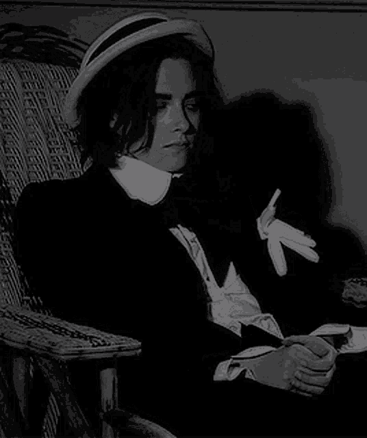 a woman is sitting in a chair wearing a hat and tie .
